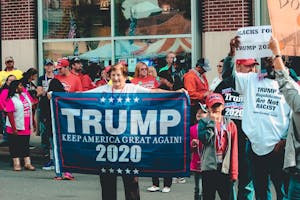 A crowded political rally in Wheeling, showcasing Trump supporters with banners and signs.